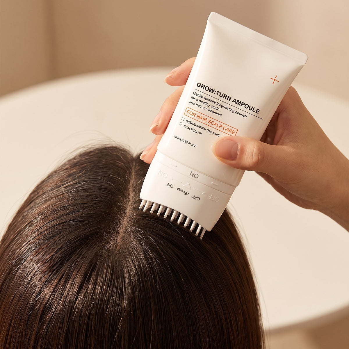 Applying Hair Revive Brush Serum along the parting with the built-in brush